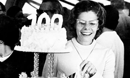 百年定时-妇女用100根蜡烛享受生日蛋糕